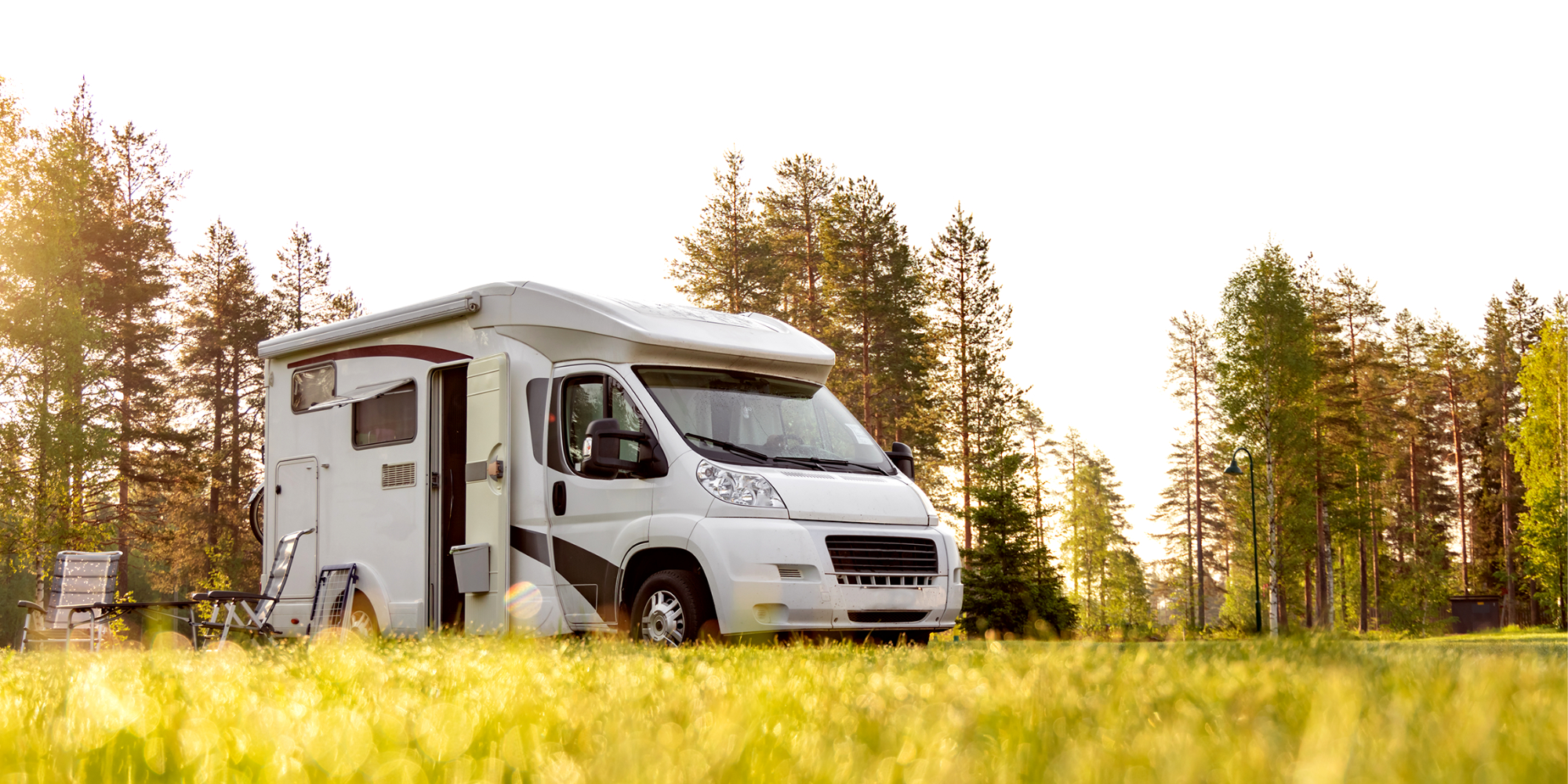 A campervan driving down a road with bikes attached to the rear